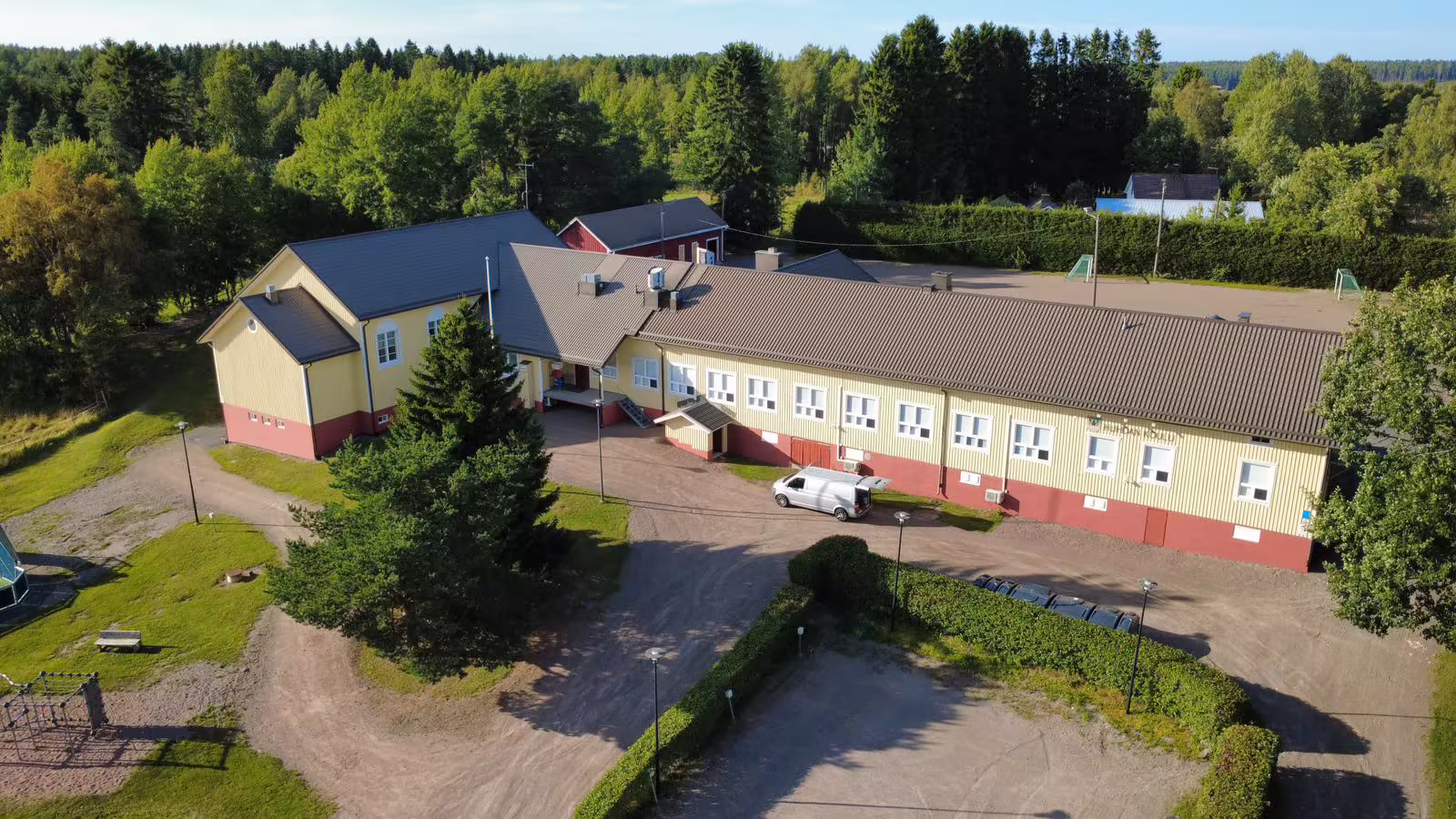 Ilmakuva O & L Maalauksen maalaamasta keltaisesta koulurakennuksesta ja sen pihasta