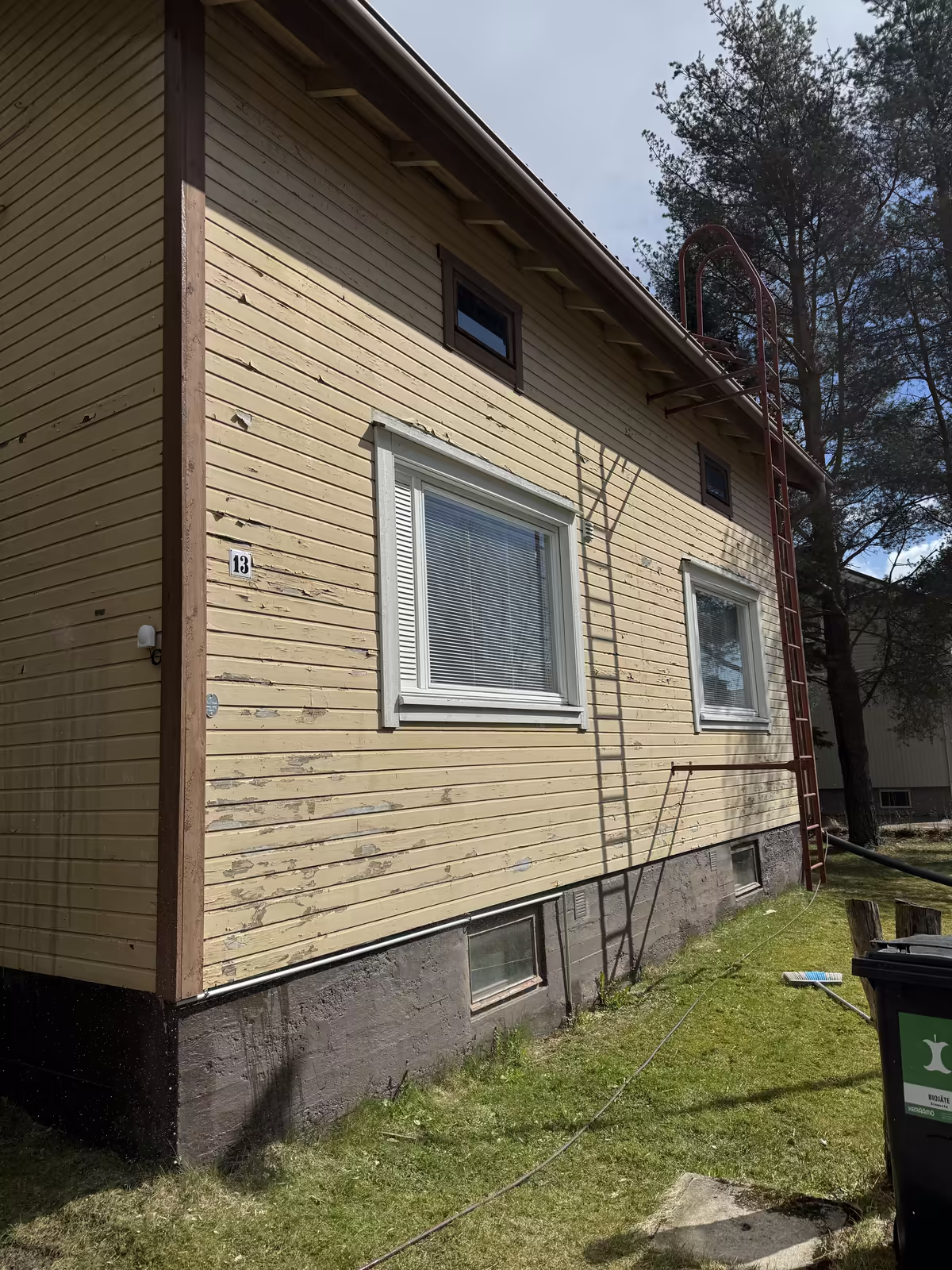 Omakotitalon puujulkisivu ennen maalausta, hilseilevä ja laikukas vaalea maalipinta