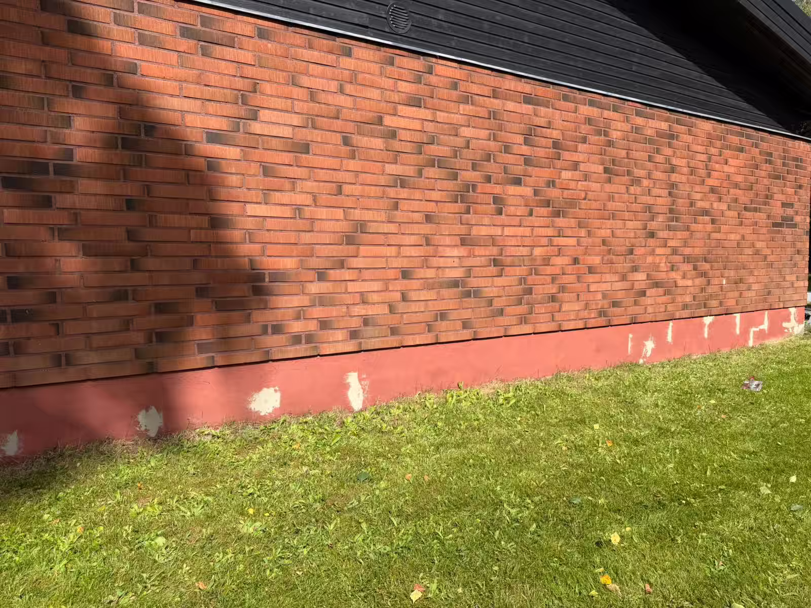 Tiilitalon sokkeli ennen maalausta, vanha punainen maali lohkeillut ja pinta laikukas