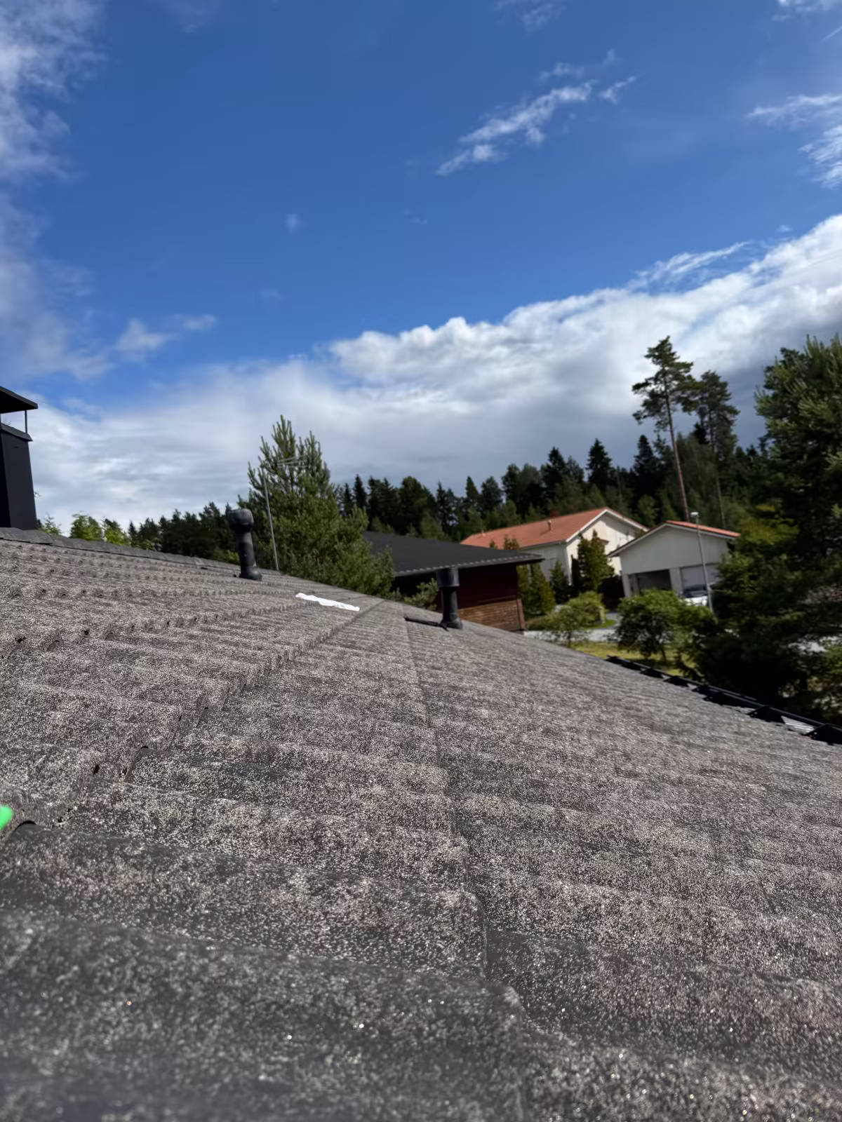 Omakotitalon tiilikatto ennen työtä, harjalta kuvattuna haalistunut ja laikukas pinta