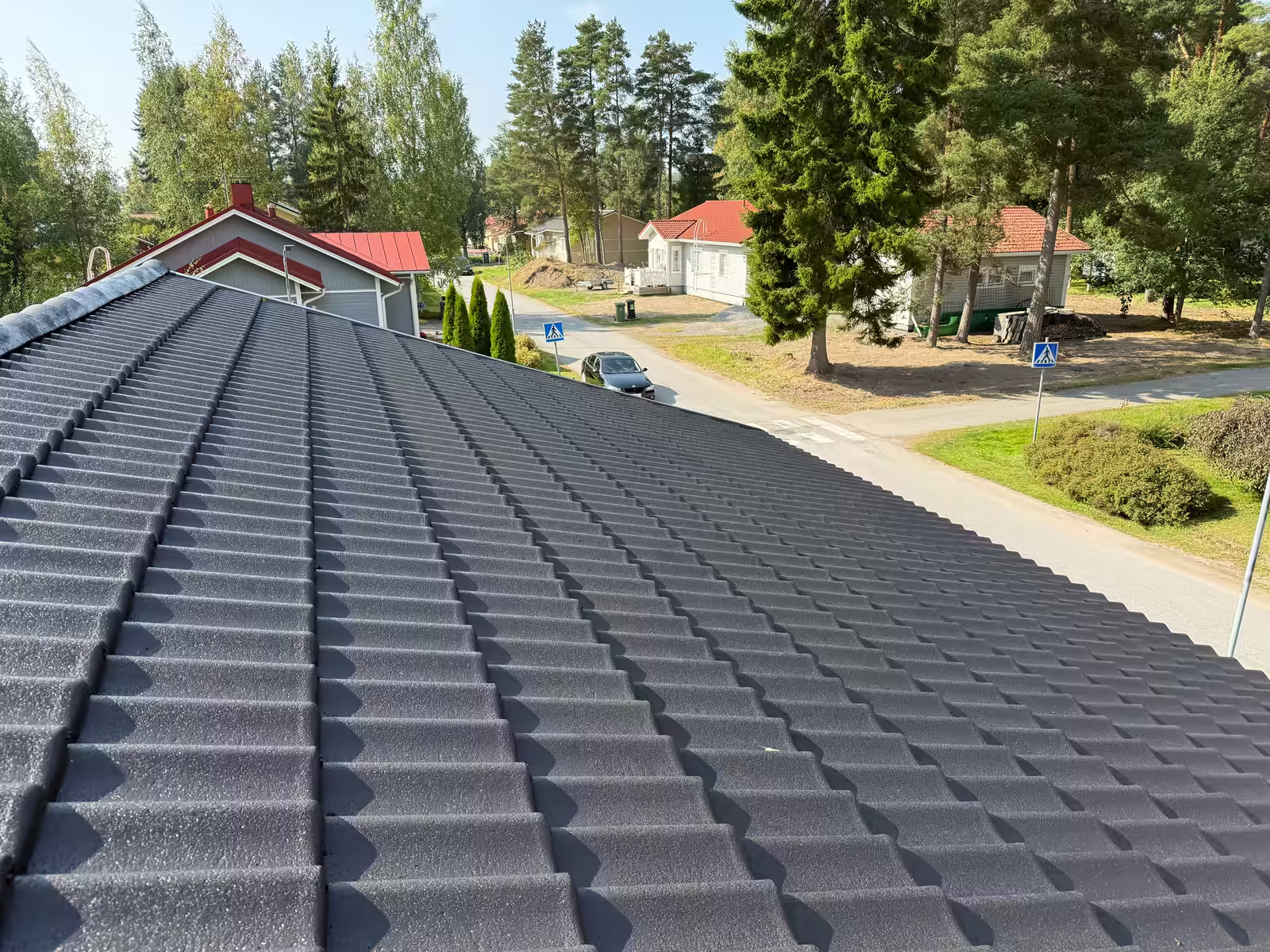 Tummanharmaaksi pinnoitettu betonitiilikatto harjalta kuvattuna